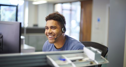 a Smiling Call Center Worker wears a headset while taking calls